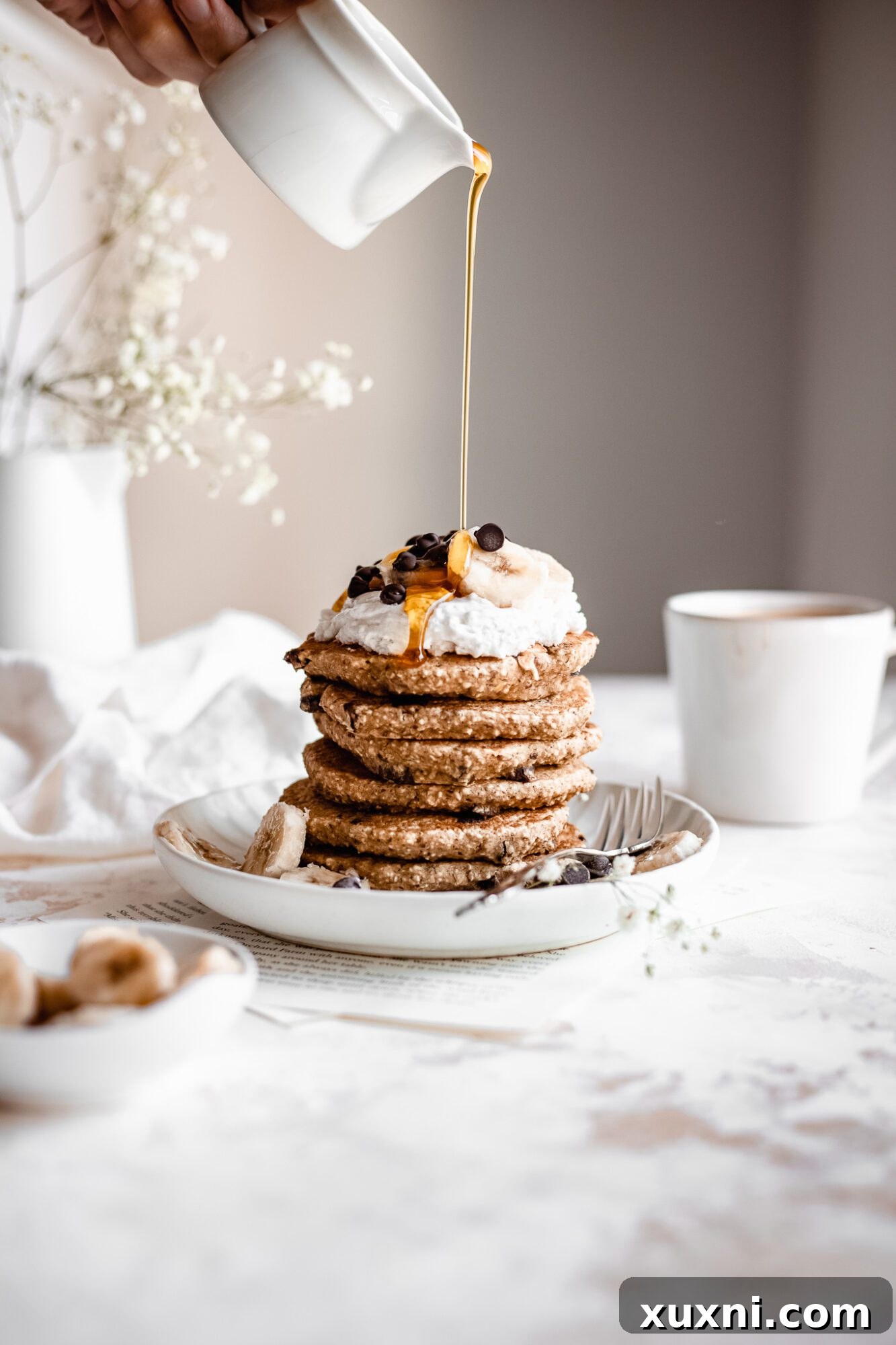 hand drizzle maple syrup on healthy chocolate chip pancakes