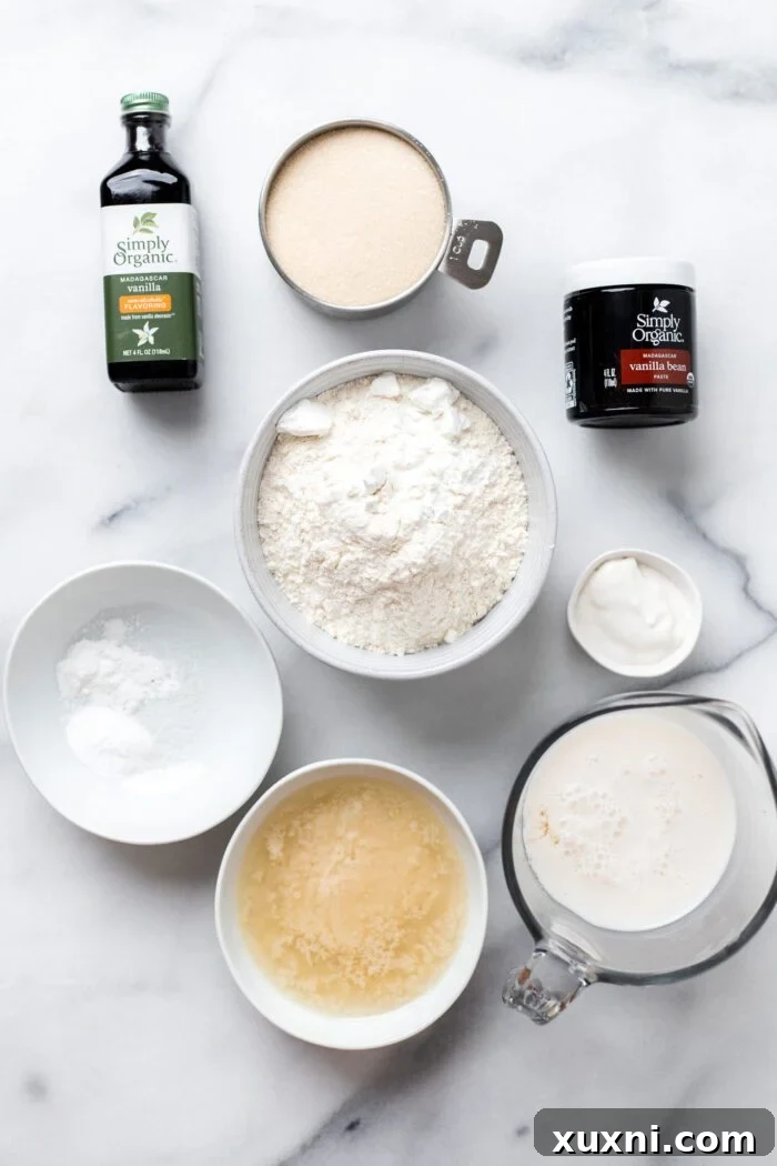 A selection of key vegan vanilla cupcake ingredients laid out, including flour, sugar, oil, and vanilla