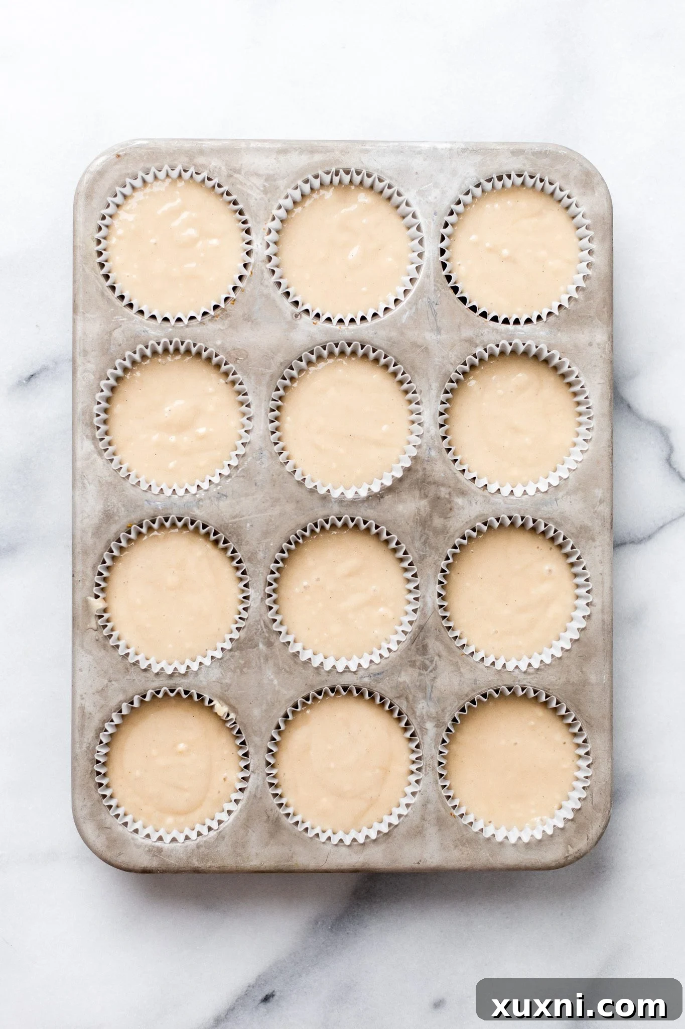Unbaked vegan vanilla cupcake batter in a lined tin, ready for the oven