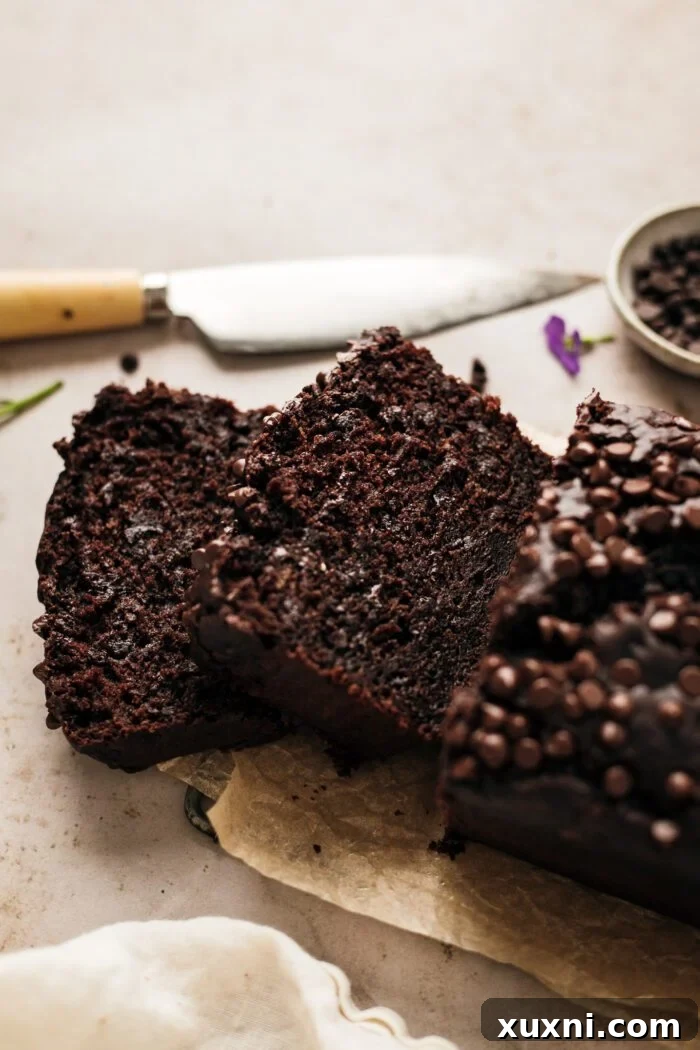 Slices of moist vegan chocolate zucchini bread, showcasing the rich chocolate and a hint of green zucchini goodness, perfect for a plant-based diet.