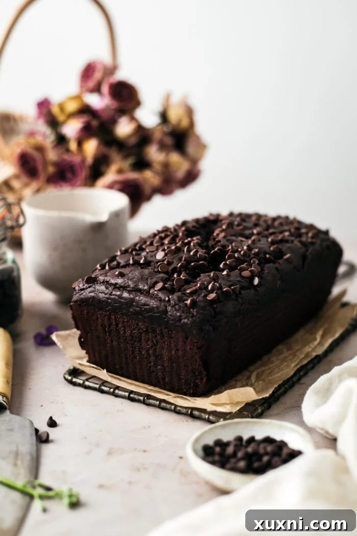 A golden-brown loaf of baked vegan chocolate zucchini bread, ready to be sliced and enjoyed, a perfect healthy dessert or snack.