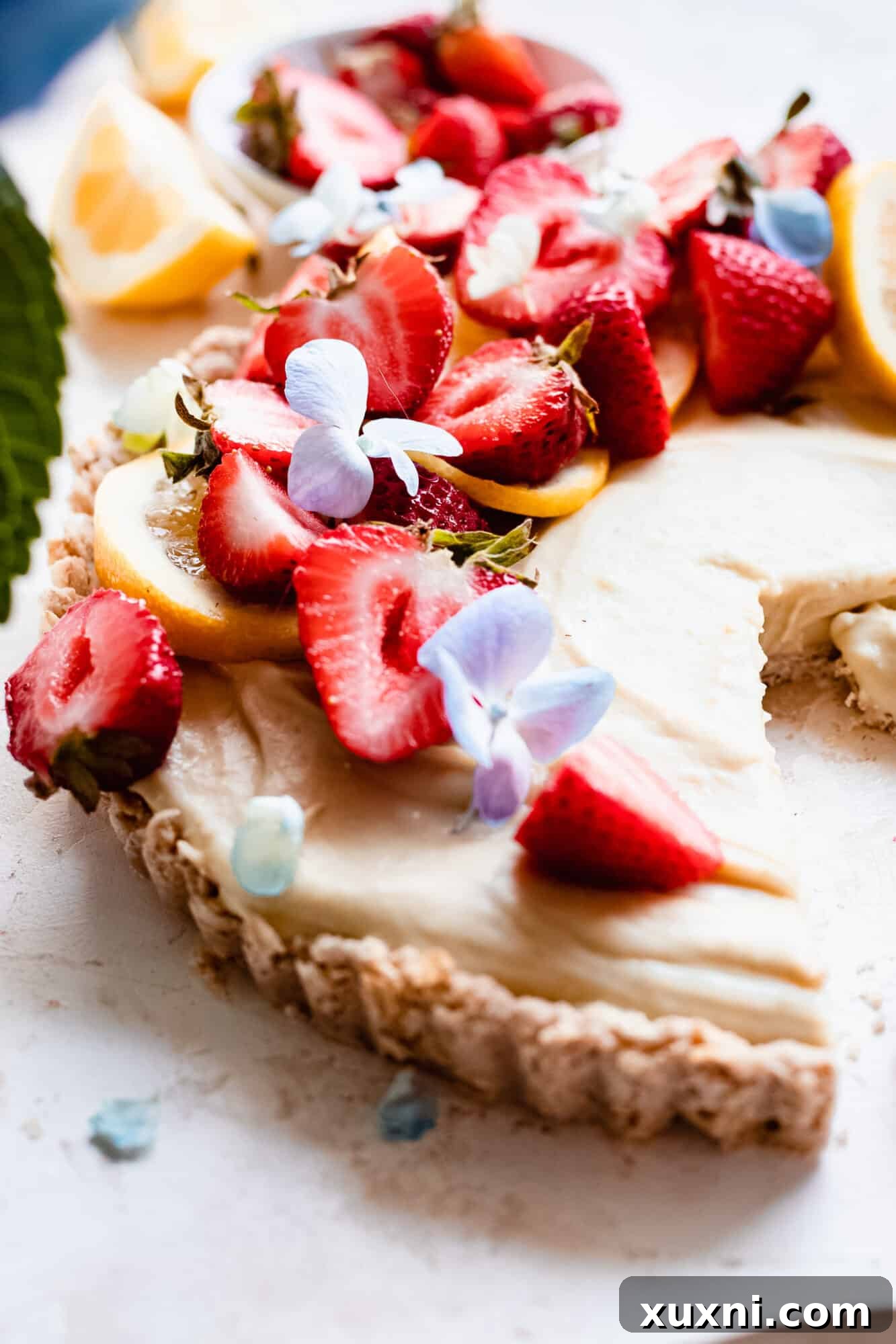 Close-up of the smooth, creamy topping of the vegan lemon tart, garnished with a single strawberry slice.