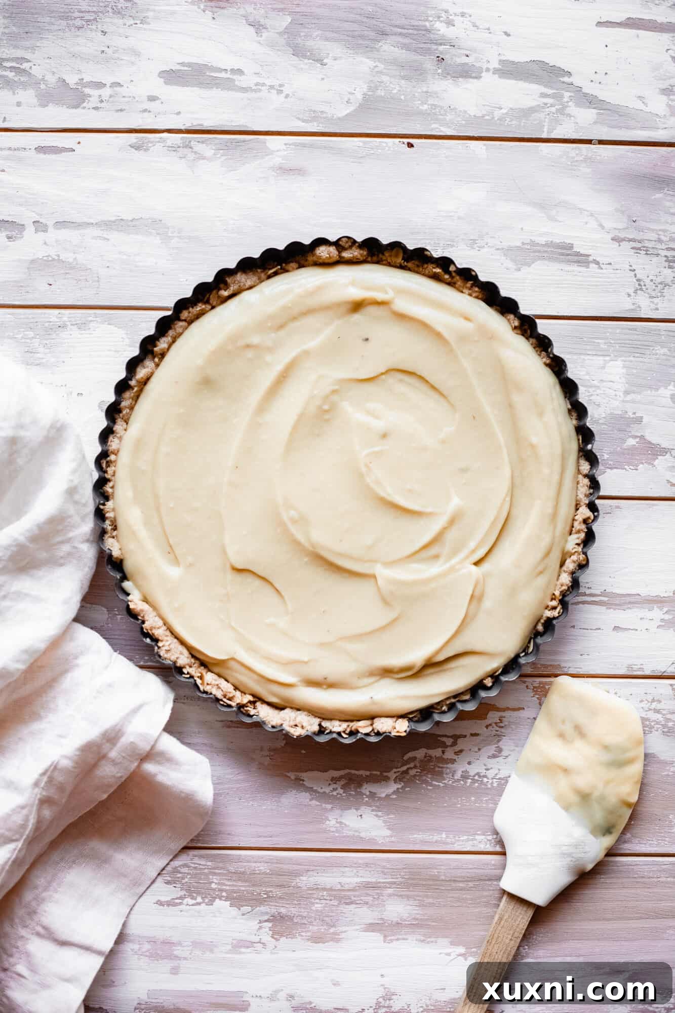 The smooth and vibrant lemon custard filling, spread evenly in a bowl, ready for the tart crust.