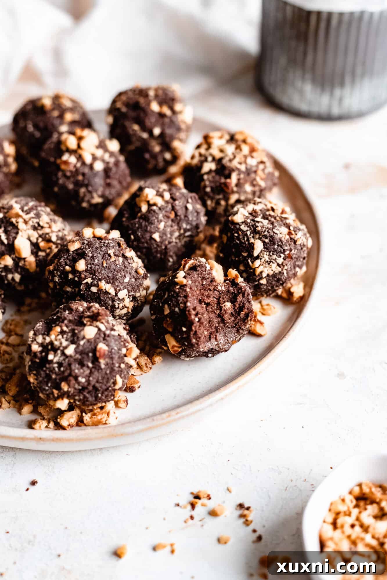 A simple white plate holding several chocolate hazelnut energy bites, artfully arranged.