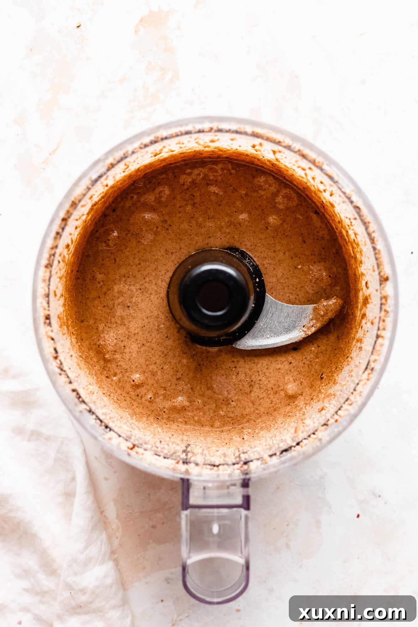 Close-up of freshly made hazelnut butter, smooth and creamy, in a food processor.
