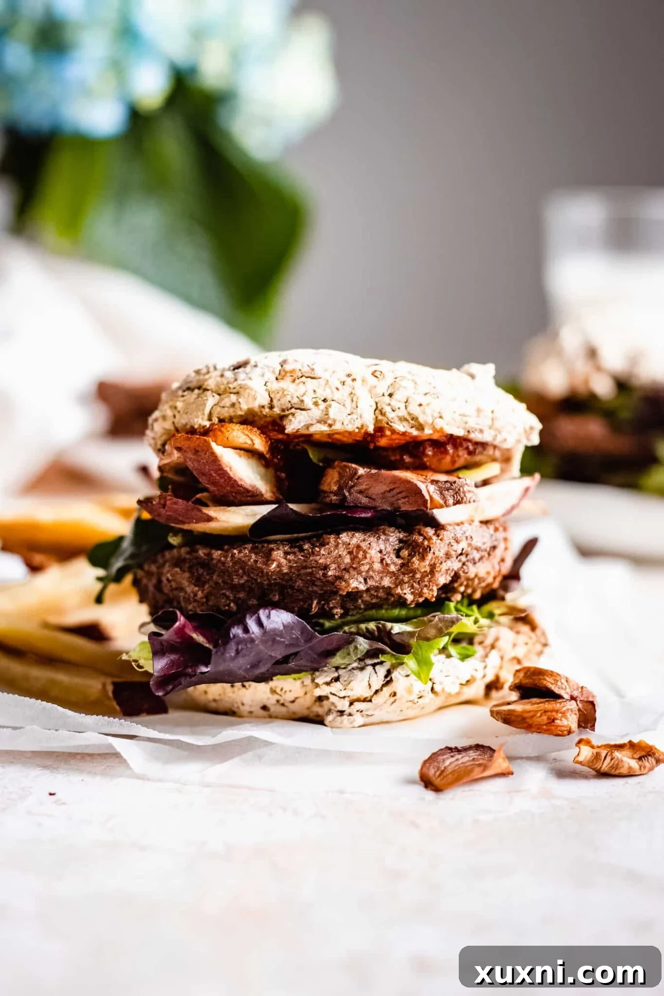 Flavorful vegan veggie burger served with sweet potato fries on a rustic wooden board.