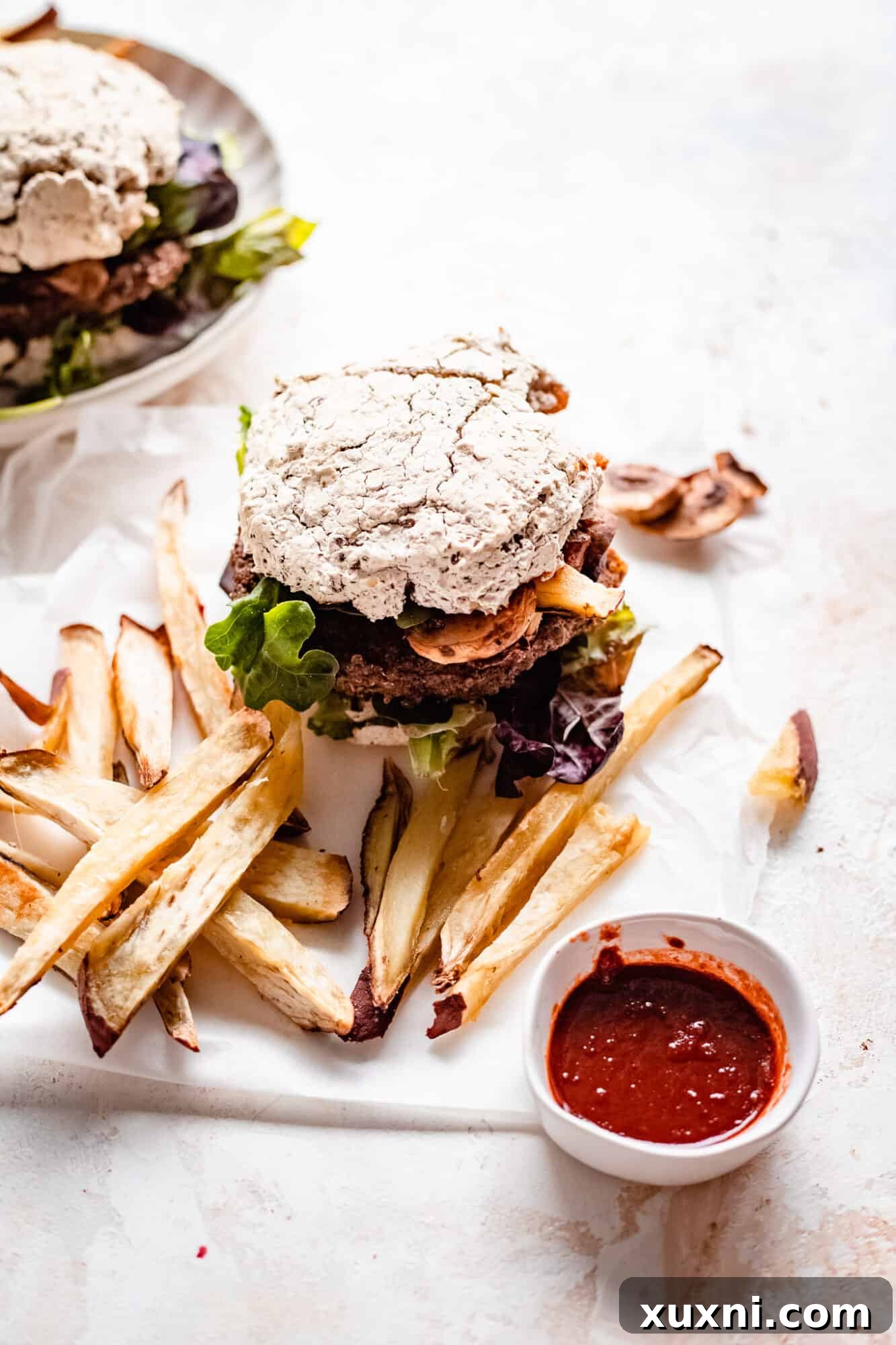 Grilled vegan quinoa veggie burger on parchment paper, ready to be served, accompanied by crispy sweet potato fries.