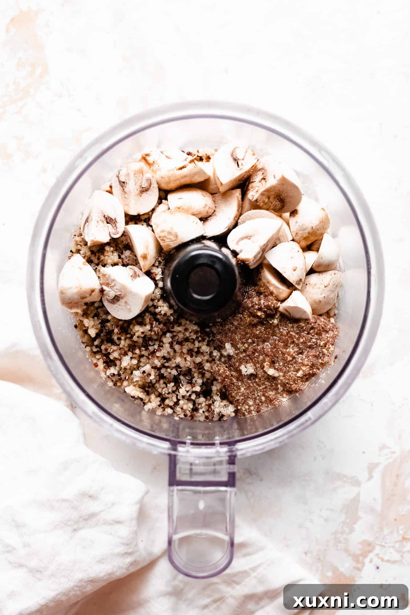 Raw mushroom and quinoa burger ingredients being prepared in a food processor.