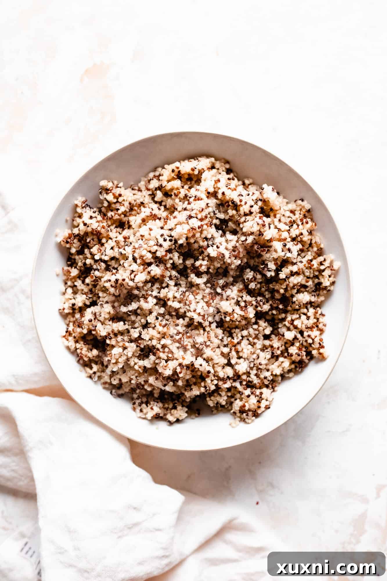 A serving of fluffy quinoa in a bowl, garnished with fresh herbs, showcasing its perfect texture.