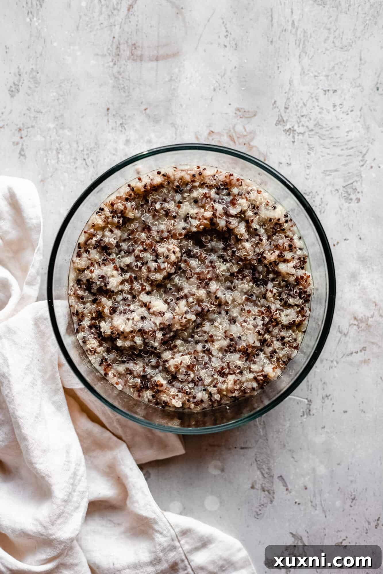 Cooked quinoa portioned into a meal prep container, alongside fresh vegetables, ready for a healthy meal.