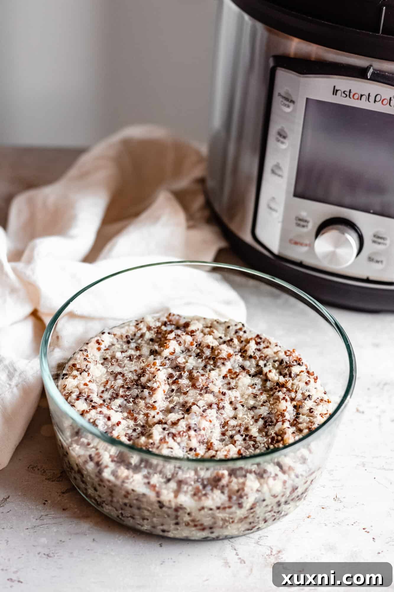 A bowl of fluffy cooked quinoa next to an Instant Pot, symbolizing easy and healthy meal preparation.