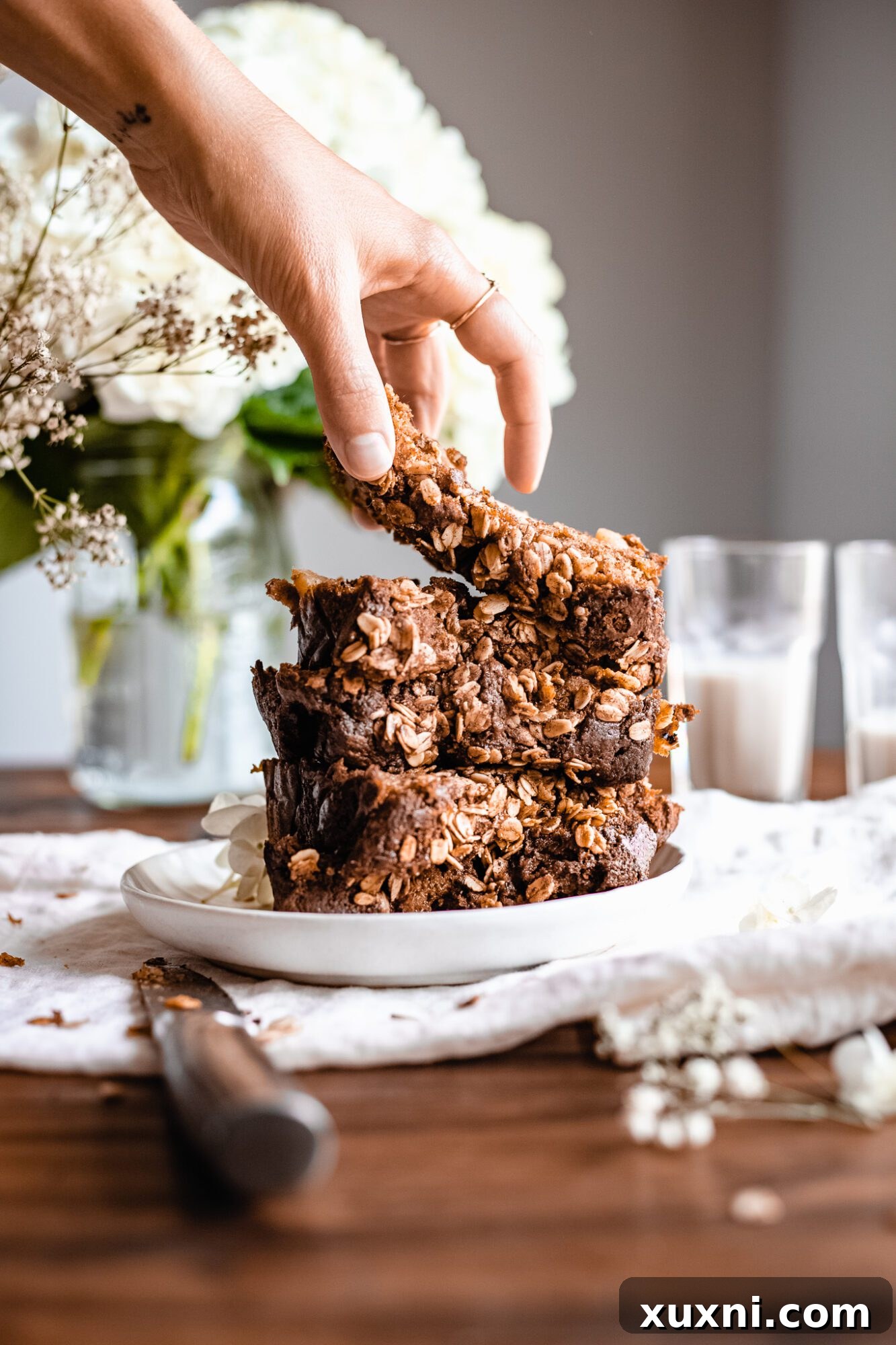 A hand reaching for a slice of warm vegan apple cinnamon bread, showcasing its inviting texture and golden crust.