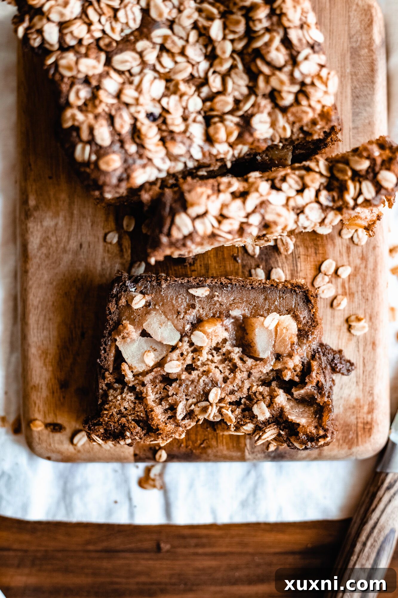 A single slice of vegan apple cinnamon bread on a white plate, highlighting the tender crumb and apple pieces within.
