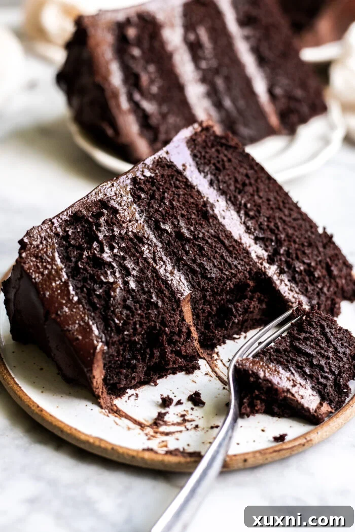 Unbelievably Moist Vegan Chocolate Cake Recipe Lasts Four Days 3 A delectable slice of vegan chocolate cake resting on a plate, revealing its beautifully layered structure and glossy chocolate frosting.