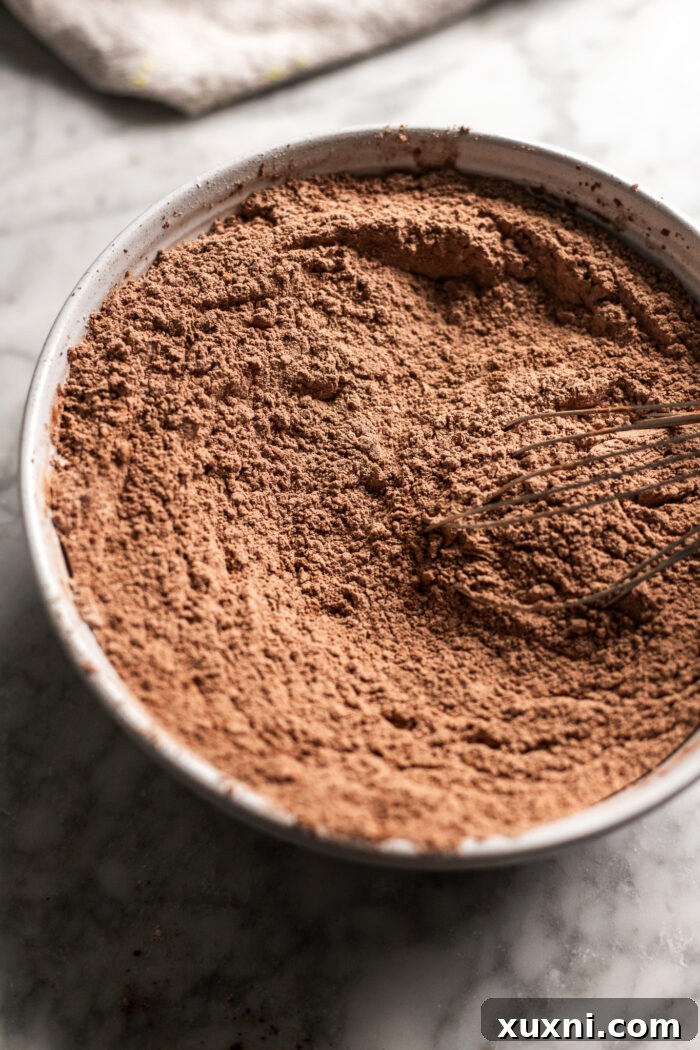 Unbelievably Moist Vegan Chocolate Cake Recipe Lasts Four Days 6 A bowl filled with dry ingredients for chocolate cake: flour, cocoa powder, sugar, baking soda, and salt, perfectly sifted and ready.