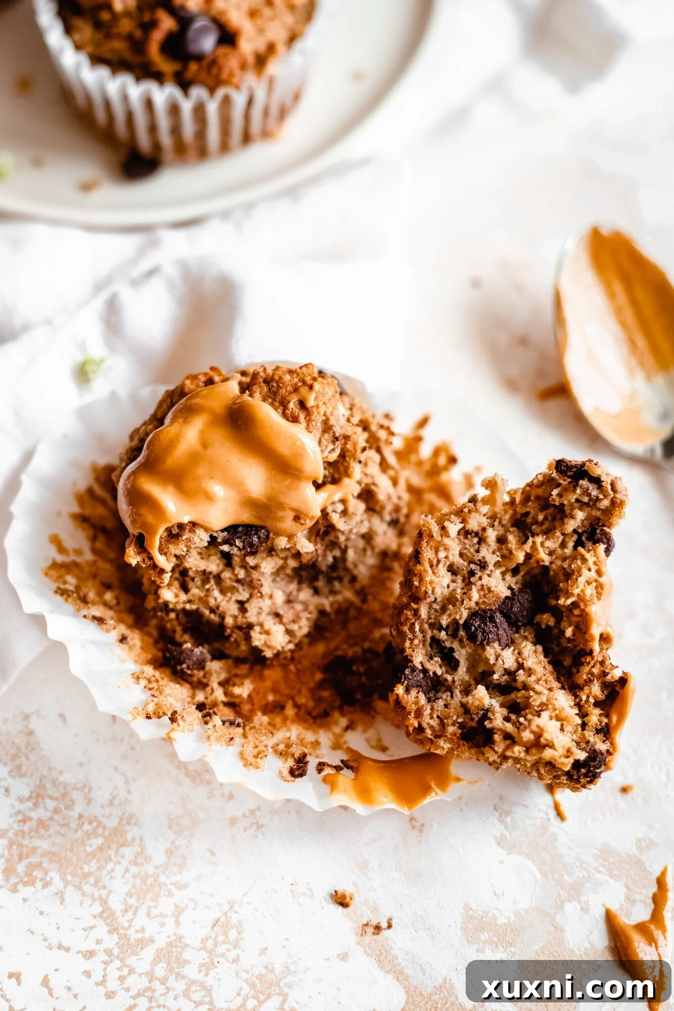A sliced peanut butter banana muffin topped with more peanut butter, showing its fluffy interior