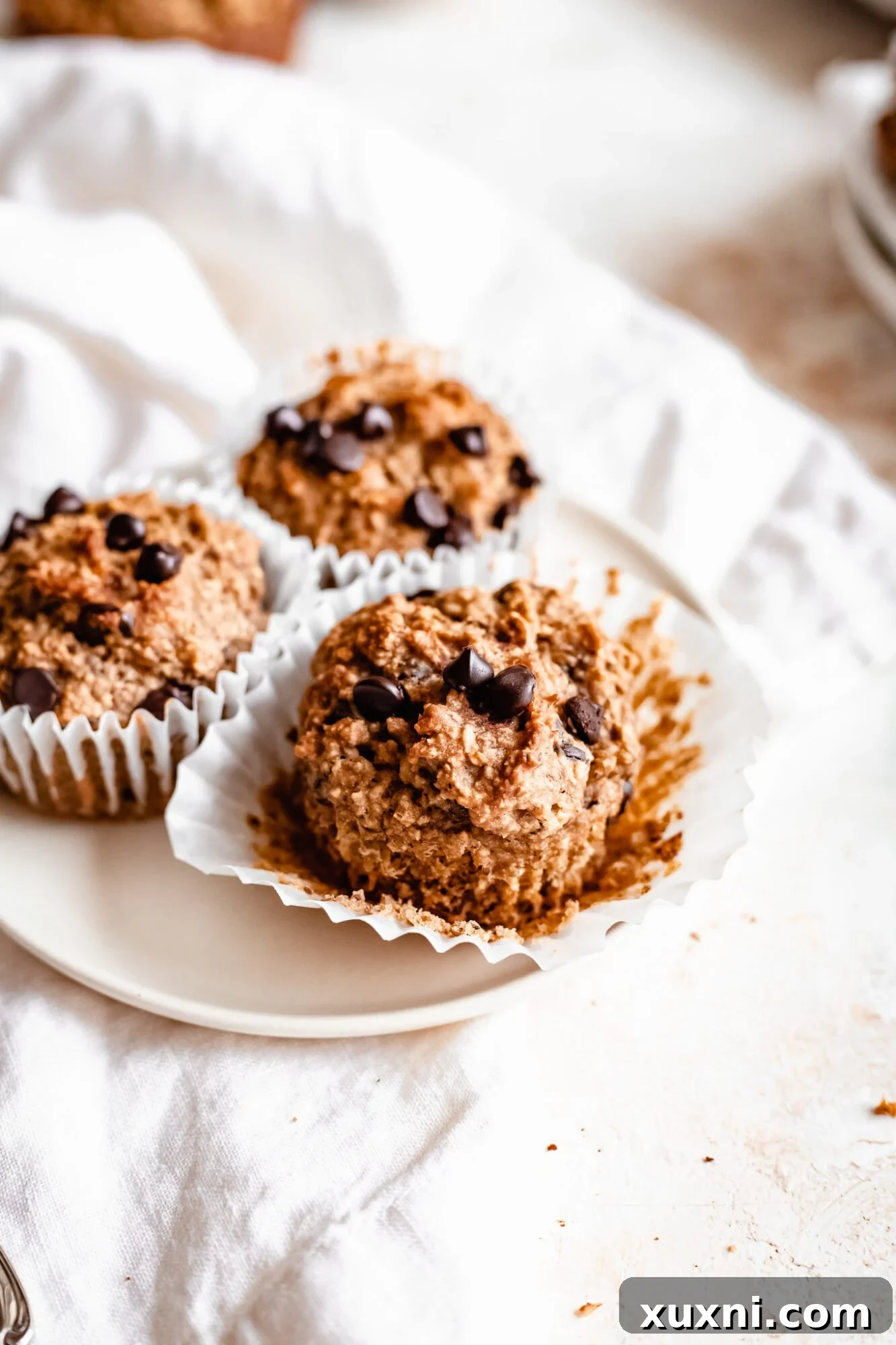Peanut butter banana muffins with liners pulled off, showing soft interior