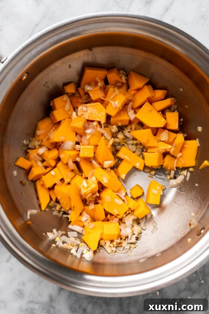 Speedy Silky Vegan Butternut Soup Coconut-Free in 30 Minutes 5 Sautéed butternut squash, minced garlic, and chopped onion mingling in a large pot, filling the kitchen with inviting aromas.