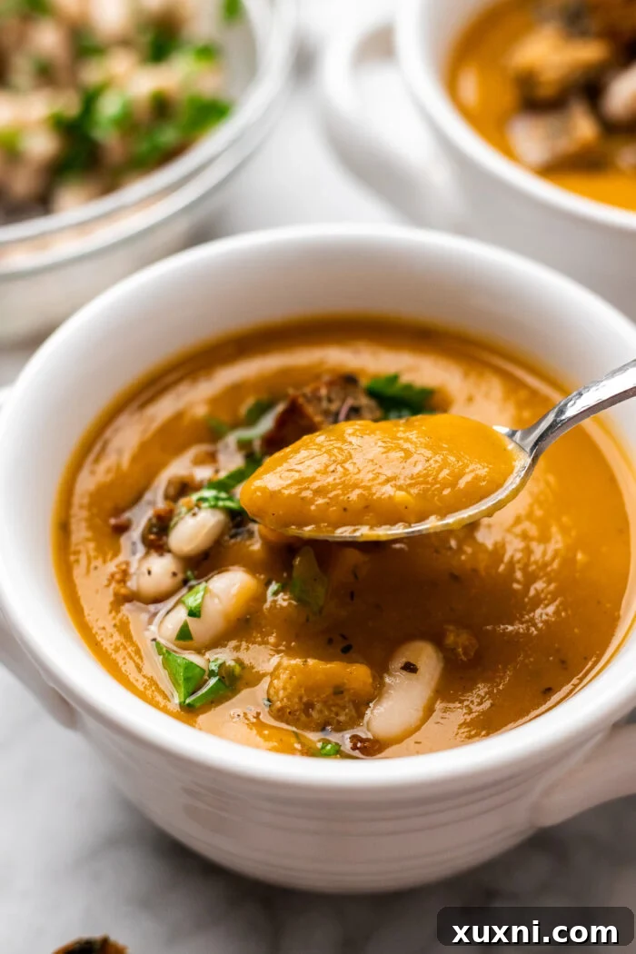 Speedy Silky Vegan Butternut Soup Coconut-Free in 30 Minutes 9 A spoon lifting a rich, creamy spoonful of butternut squash soup, showcasing its smooth texture.