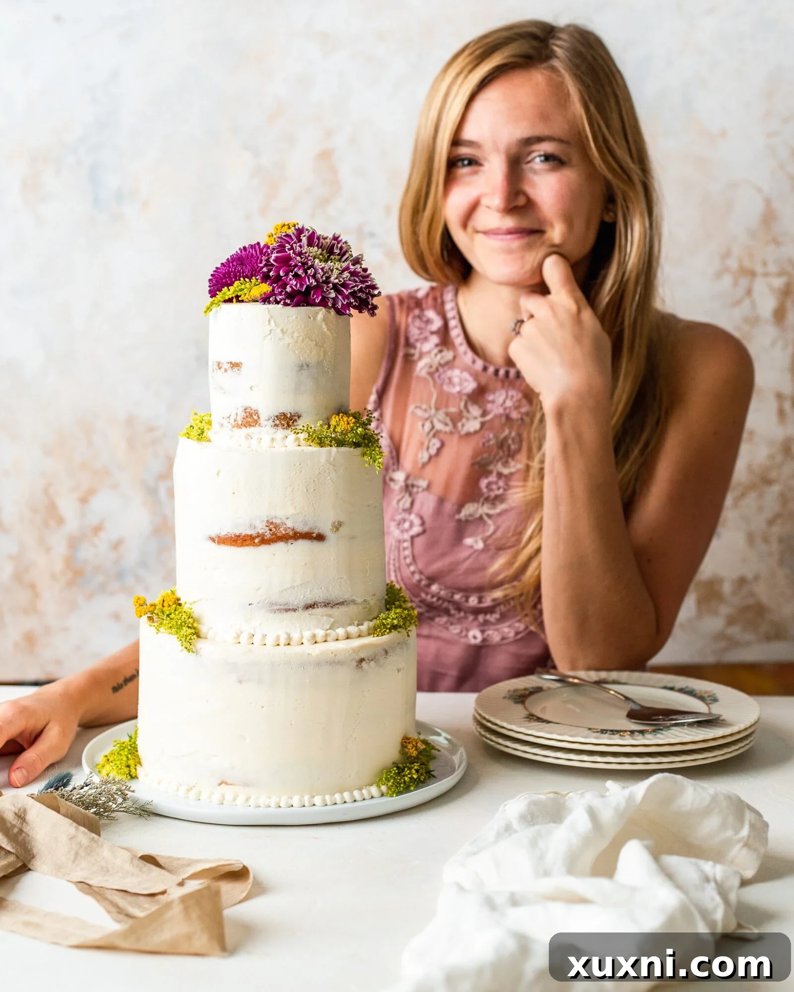 A baker proudly showcasing a beautiful homemade vegan wedding cake, highlighting the joy of DIY baking