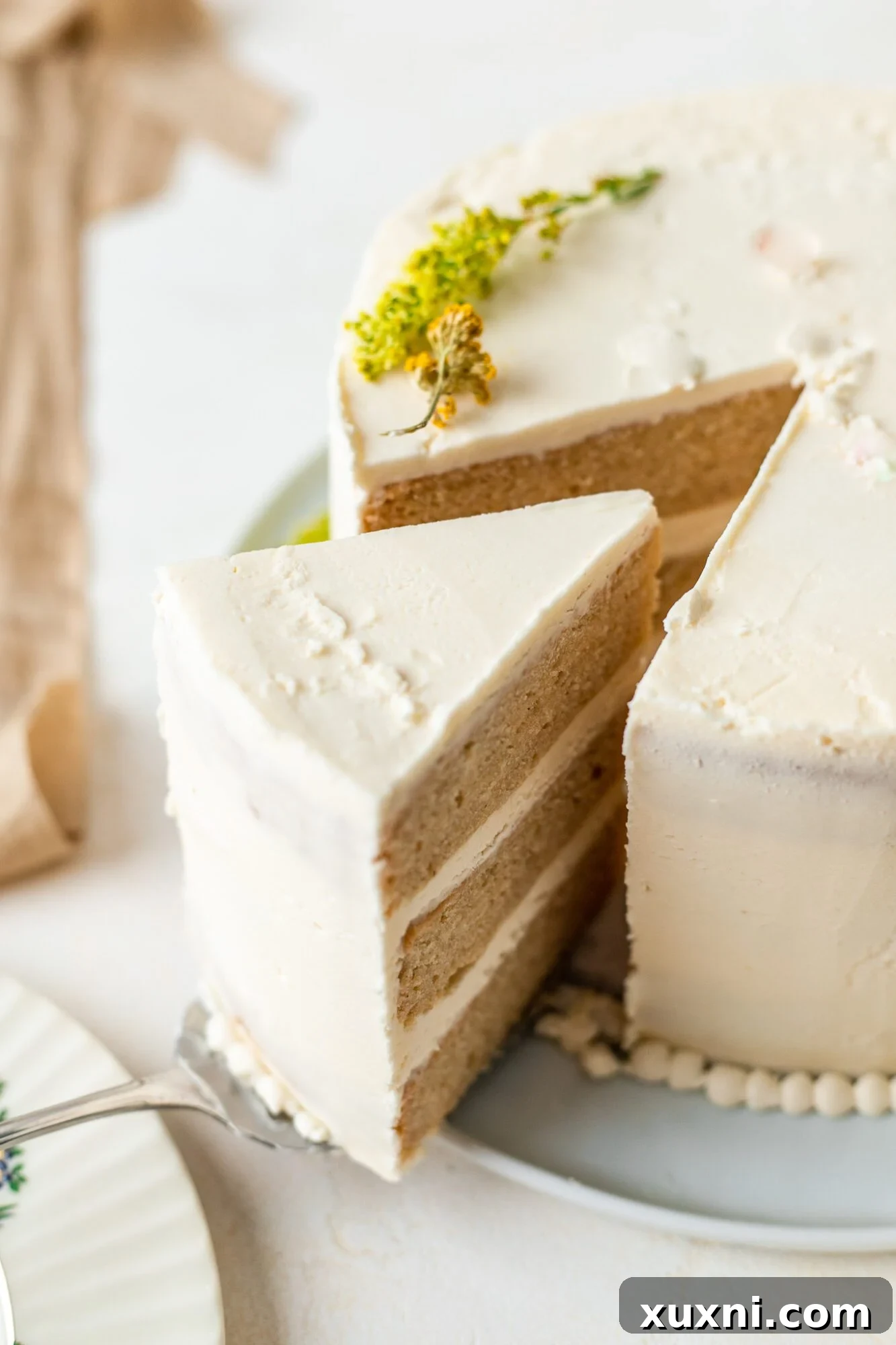 A perfectly cut slice of moist vegan wedding cake with creamy frosting and fresh berries