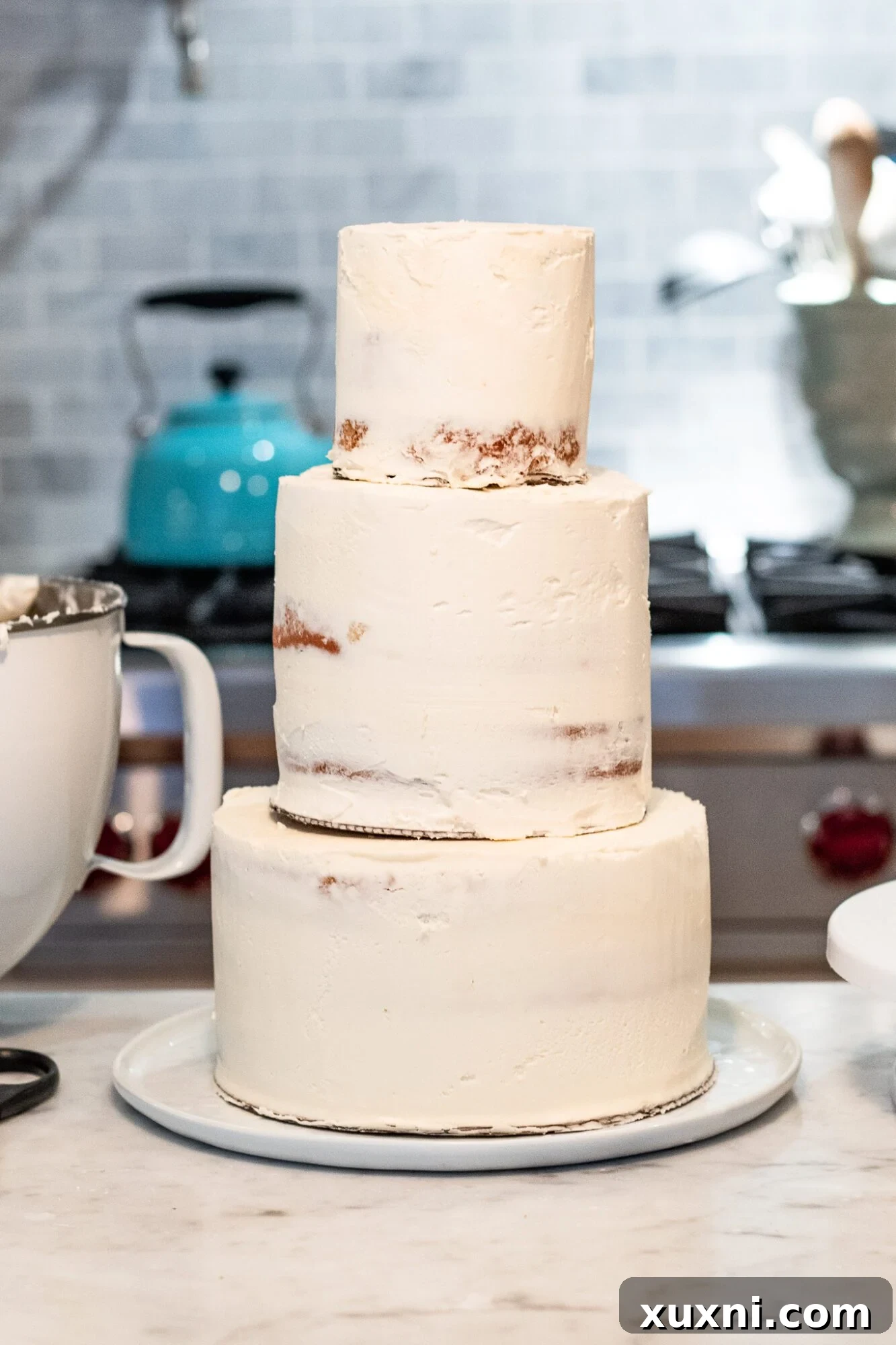 Close-up of a multi-tier vegan wedding cake being carefully stacked with support dowels