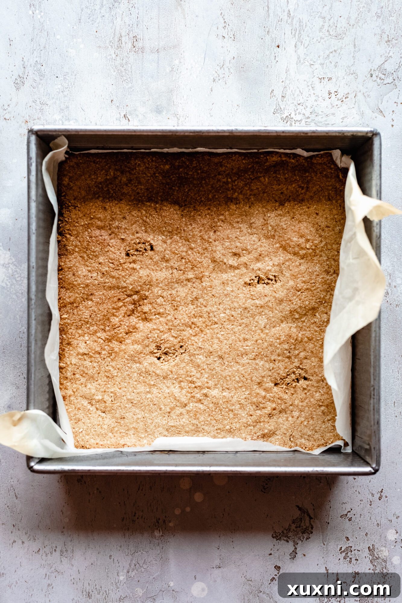 Golden-brown oat flour crust, perfectly baked in a pan, providing a sturdy base for the pumpkin pie filling.