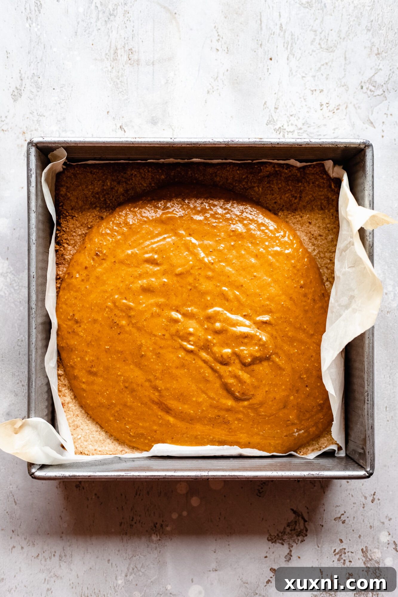 A close-up of the smooth, vibrant pumpkin pie bar filling in a food processor, ready to be poured onto the crust.