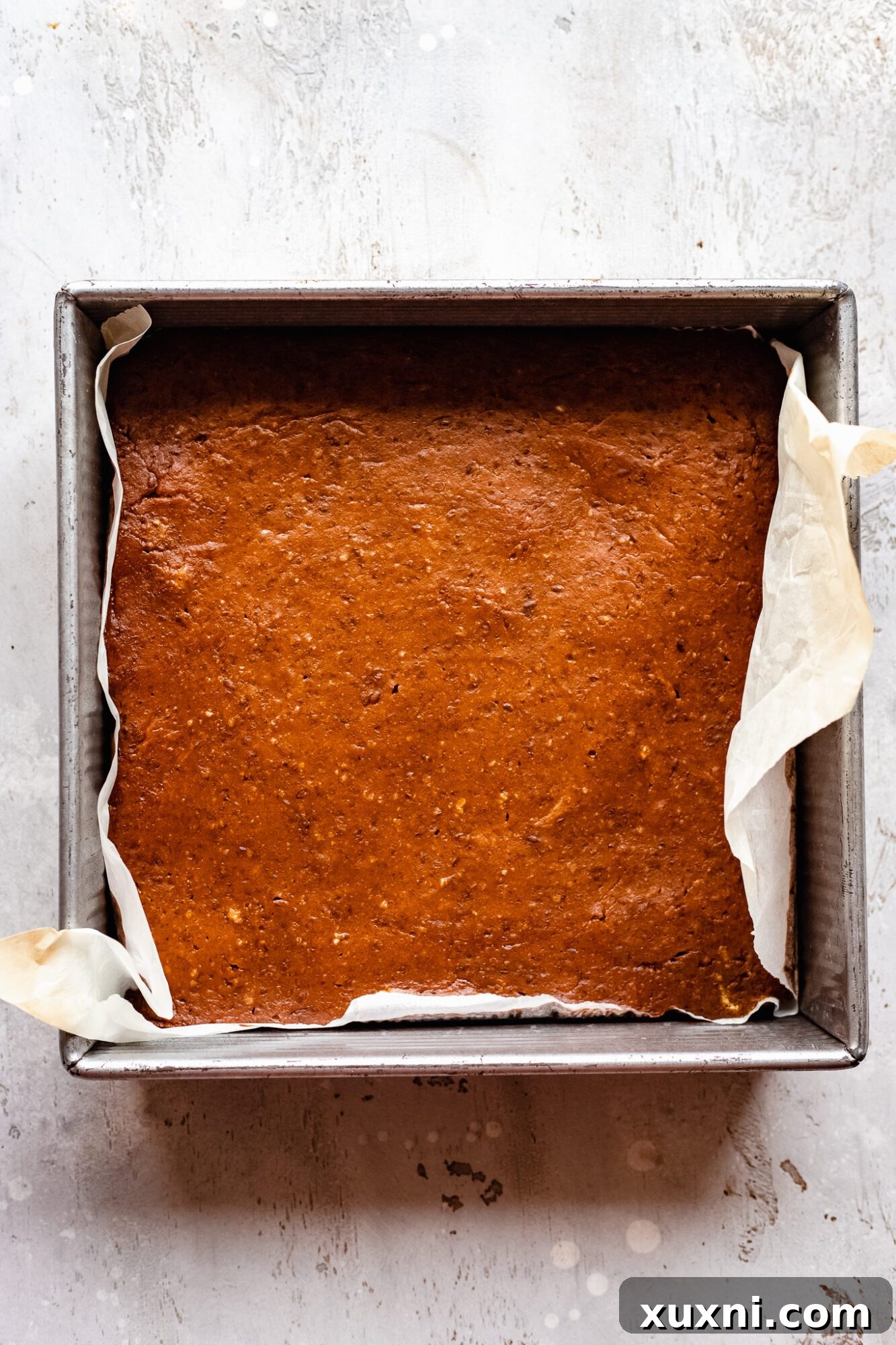 Freshly baked pumpkin bars straight from the oven, showing a slightly darker top layer and set edges.