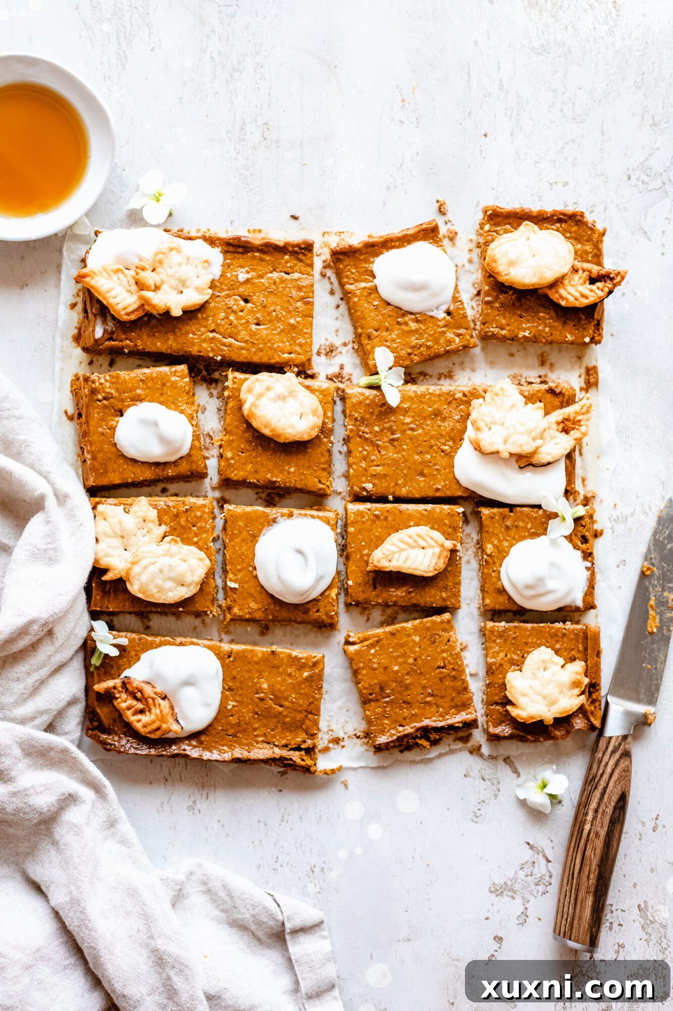 A slice of vegan pumpkin pie bar topped with fluffy coconut whipped cream, ready to be enjoyed.
