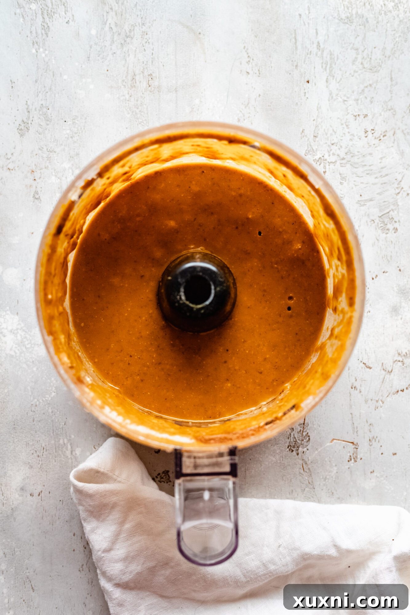 Pumpkin puree and other filling ingredients being blended smoothly in a food processor, creating a vibrant orange mixture.