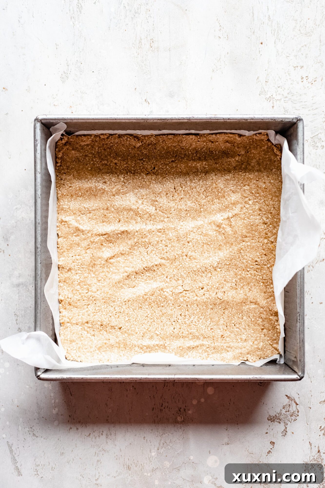 Unbaked pumpkin pie crust, made from oat flour, pressed into a baking pan, ready for blind baking.