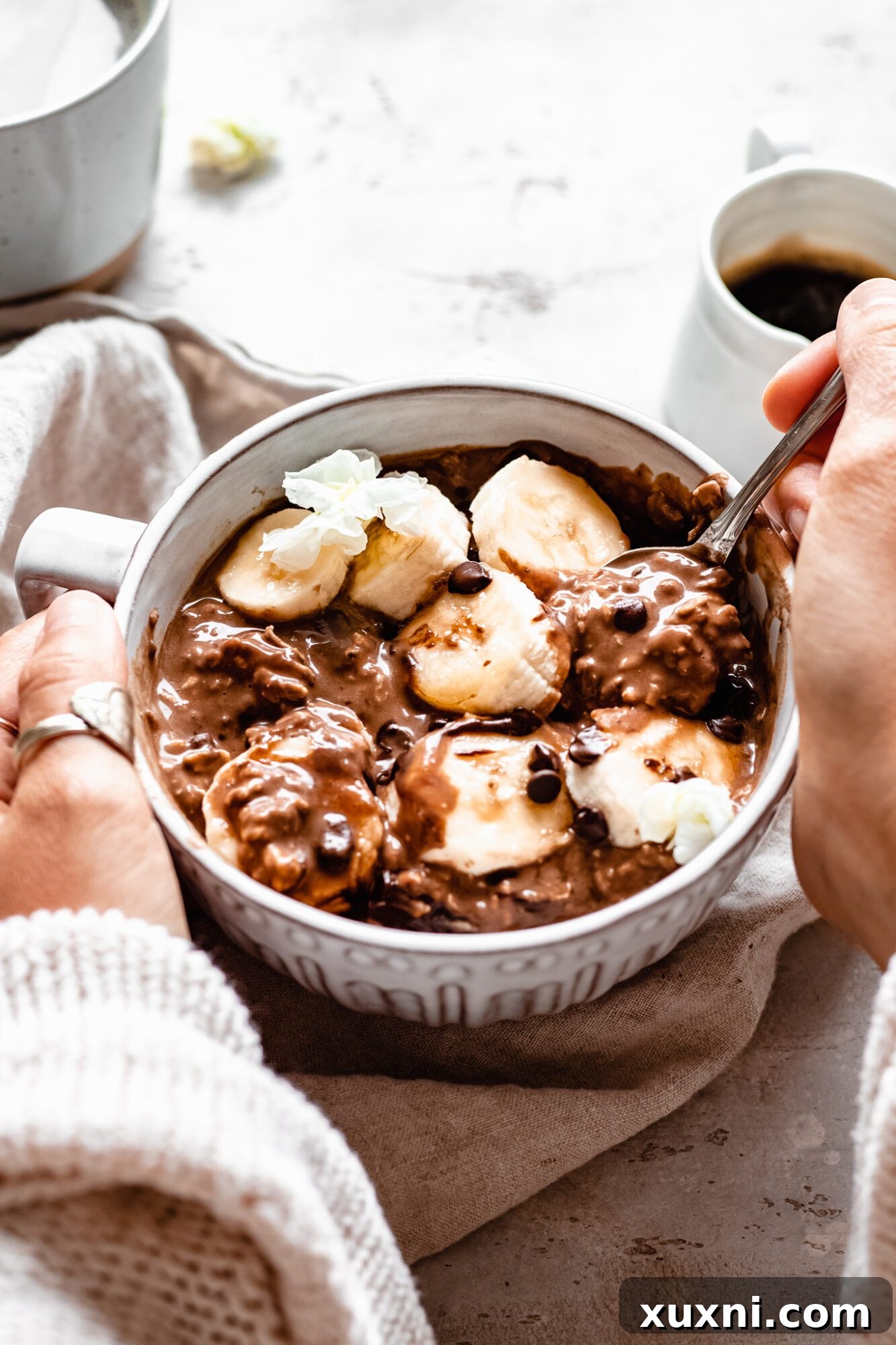 hands holding bowl of mocha overnight oats with spoon