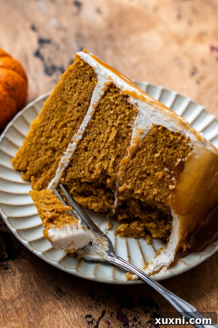Bitten slice of vegan pumpkin cake, highlighting the creamy frosting and tender cake interior.
