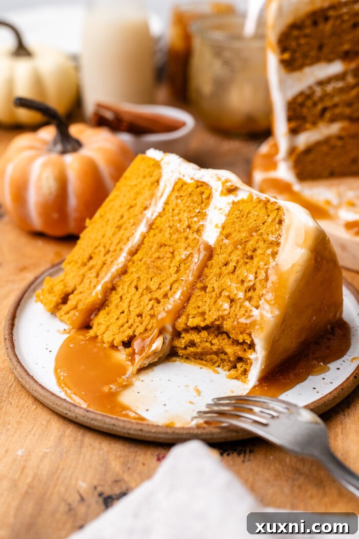 Bitten slice of vegan pumpkin cake with creamy white frosting, showing the distinct layers.