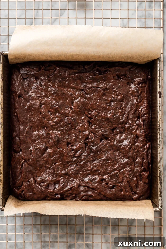Freshly baked vegan brownies, removed from the oven and cooling in the pan, showing their perfect crinkle tops.