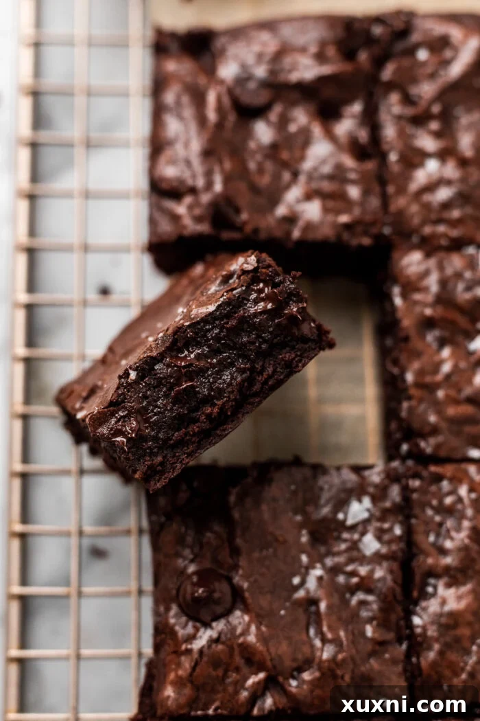 A single fudgy vegan brownie square being lifted from the pan, showing its thick, rich texture.
