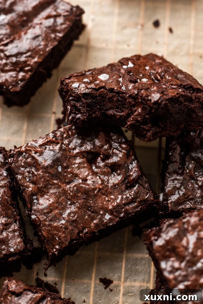 A delicious vegan brownie with a perfect crinkle top, a bite taken out to reveal its fudgy interior.