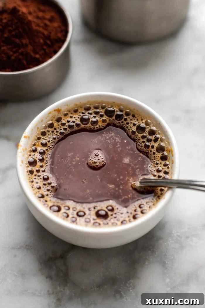 Mixing ground flaxseed with coffee to create a vegan flax egg, an essential binding agent for the brownies.