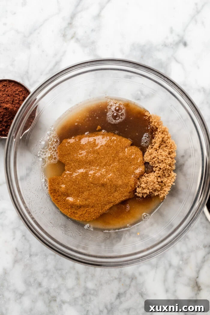 Combining the flax egg, aquafaba, sugars, and vanilla extract in a bowl, whisking vigorously for smooth integration.
