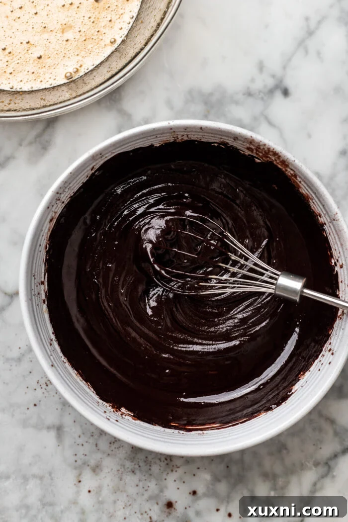 Preparing the rich chocolate fudge by whisking hot melted vegan butter, vegan chocolate chips, and cocoa powder.