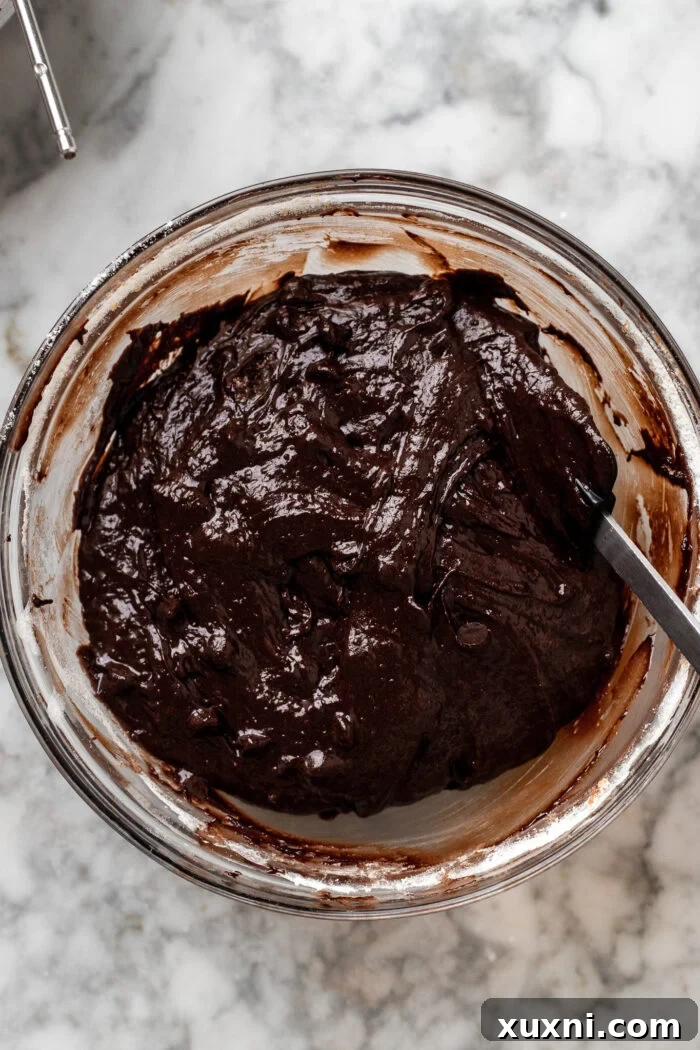 Folding in the all-purpose flour and additional vegan chocolate chips into the brownie batter until just combined.