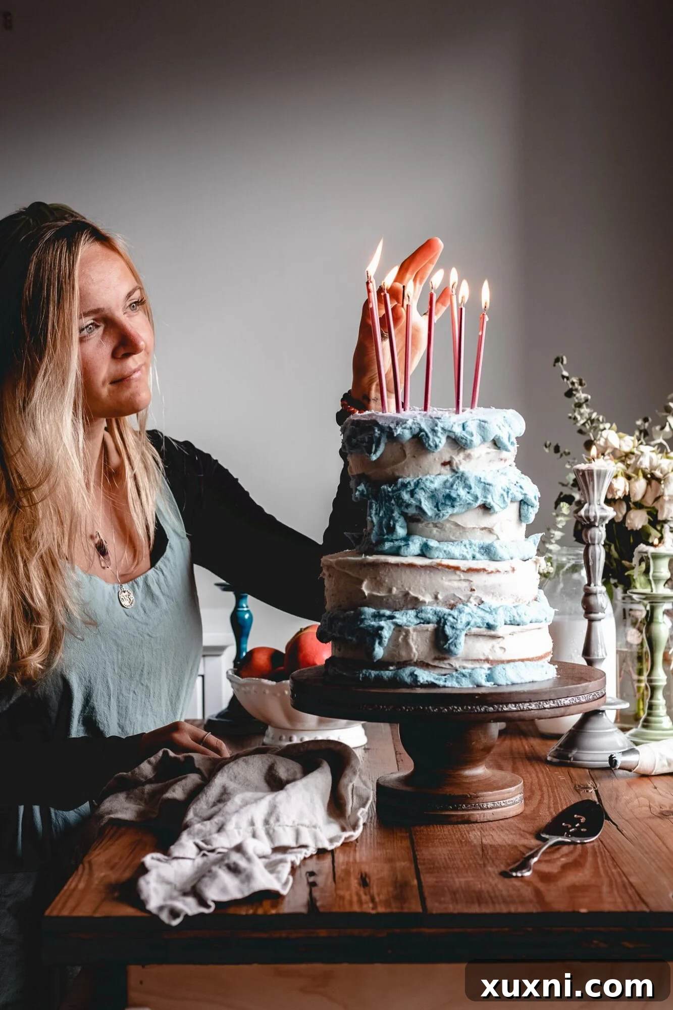 A beautifully decorated vegan Sleeping Beauty birthday cake with a slightly crooked top tier, adorned with blue frosting drips and pink candles, evoking the charm of Aurora's 16th birthday cake.