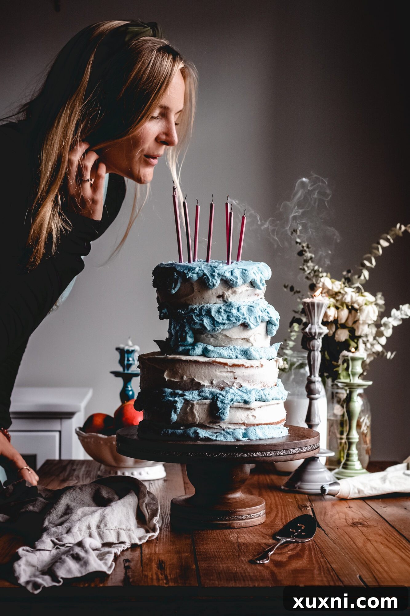 A person joyfully blowing out the pink candles on the vegan Sleeping Beauty cake, a perfect end to a magical celebration.