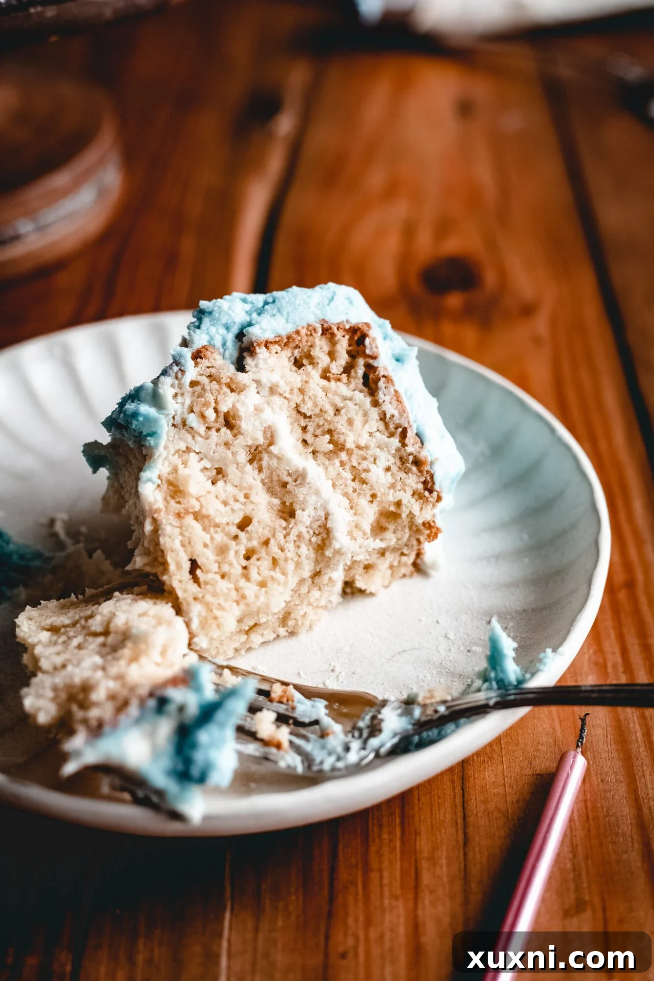 A perfect slice of the vegan Disney birthday cake on a white cake plate, revealing multiple layers of tender vanilla cake and smooth buttercream.