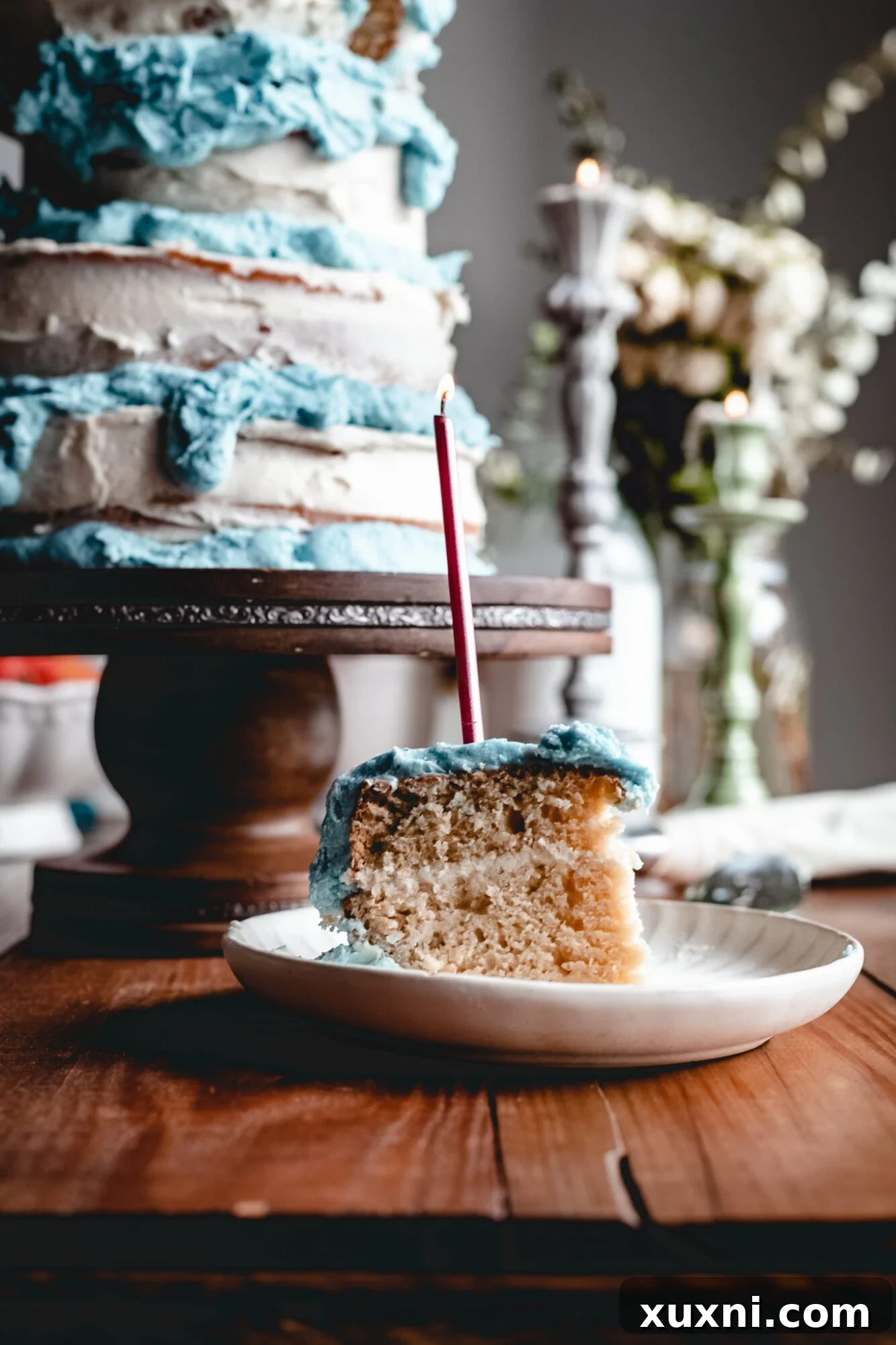 A beautifully decorated slice of vegan Sleeping Beauty birthday cake with a single lit candle, ready for celebration.