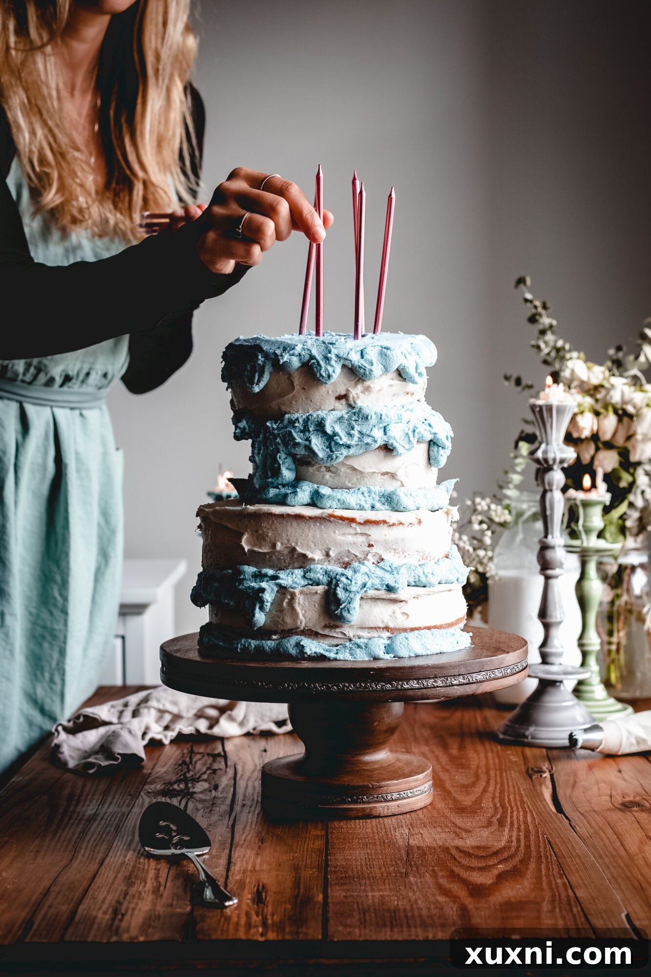 A hand carefully placing colorful pink candles into the top tier of the vegan Sleeping Beauty birthday cake.