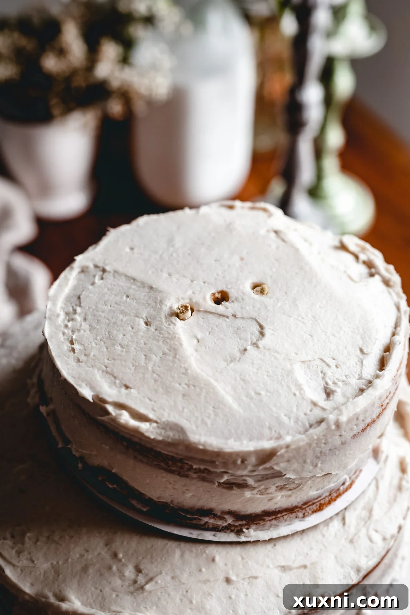 Close-up of the partially assembled cake, showing cake dowels strategically placed within a frosted cake tier for support.