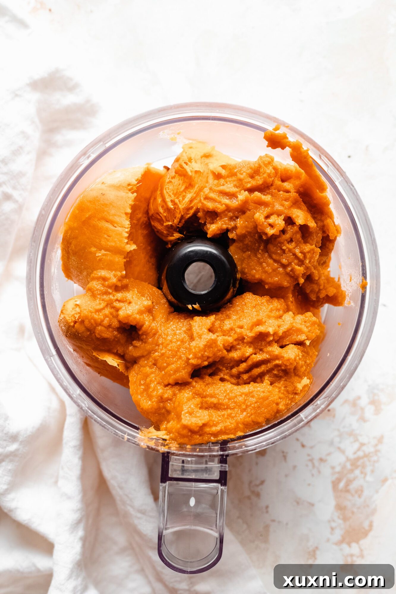A bowl filled with rich pumpkin puree and another with chunks of baked sweet potato, ready for blending.