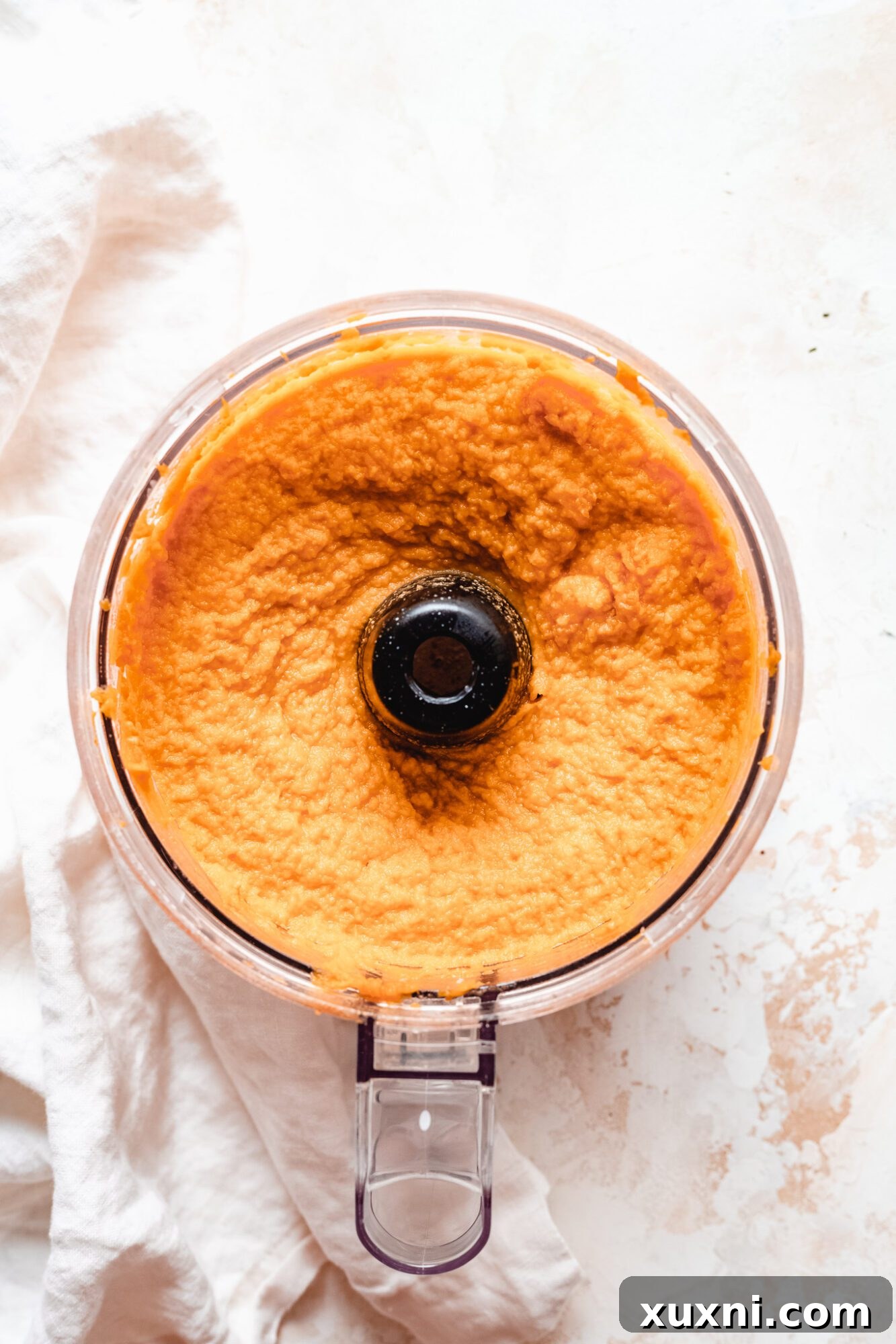 Pureed pumpkin and sweet potato mixture in a blender, showcasing its smooth and vibrant texture.